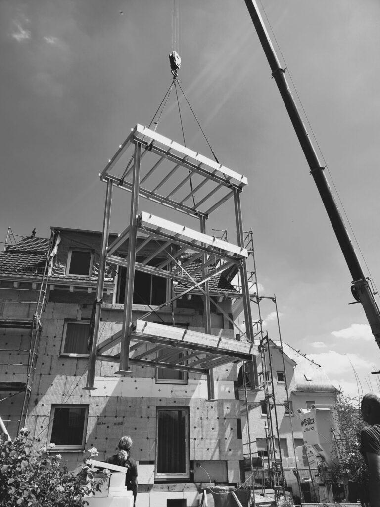 Metallkonstrukt schwebt vor Haus.